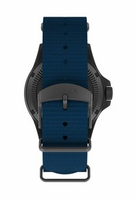 Sort ur med et struktureret navyblåt stofarmbånd, der har en metalspænde og en rund urskive med detaljerede markeringer.