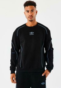 Sudadera negra con costuras azules, con mangas largas y cuello redondo. Logo en el pecho y costuras de acento en las mangas.