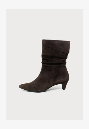 Dunkelbrauner Wildleder-Kniestiefel mit lockerem Schaft, spitzer Spitze und niedrigem Kittenabsatz auf hellem Hintergrund.