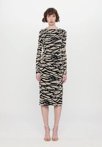 Midi-jurk met lange mouwen, featuring een beige en zwart abstract patroon. De stof is rekbaar, met een aansluitende pasvorm en ronde halslijn.