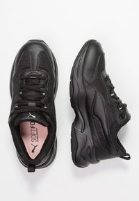 Black sneakers featuring a textured leather and mesh upper, padded collar, and a contrasting pink insole labeled "SOFTFOAM."
