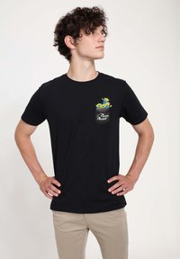 Sort t-shirt med en lomme, der har tre grønne aliens og teksten "Pizza Planet!" i hvid. Materialet er bomuld med en glat tekstur.