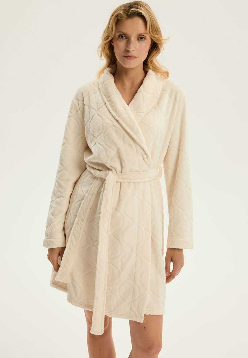 Beżowy szlafrok z polaru z pikowanym wzorem w diamenty, z kołnierzem szalowym, długimi rękawami i wiązanym paskiem w talii.