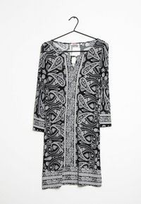 Svartvit mönstrad klänning med v-ringning, med trekvartslånga ärmar och intrikata paisleymönster över tyget.