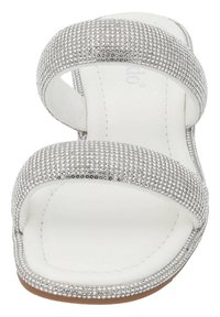 Zilveren sandalen hebben twee brede banden die bedekt zijn met kleine rhinestones, een gladde witte binnenzool en een platte bruine zool. Minimalistisch ontwerp.