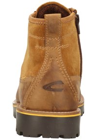 Brown suede ankle boot with leather accents, featuring a zipper on the side and textured rubber sole for grip. Simple logo detail on heel.