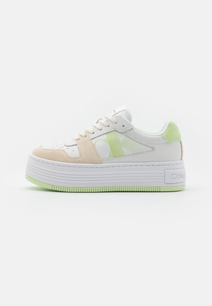 Sneaker bianco e beige con suola a piattaforma, caratterizzata da accenti verde lime, materiali in pelle e suede, e un logo prominente sul lato.