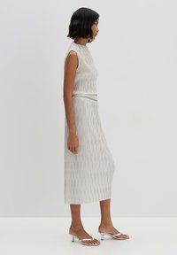 Lichtgrijze geribbelde tweedelige set met een mouwloos topje en een midi-rok, met verticale lijnen en bijpassende zilveren haksandalen.