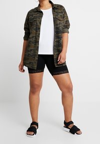 Särmäkuosiset paitatakit, valkoinen t-paita, mustat pyöräilyshortsit pitsireunuksella ja mustat sandaalit valkoisilla pohjilla. Rentoa pukeutumista, jossa on kontrastisia tekstuureja.