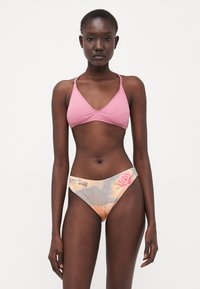 Haut de bikini triangulaire rose associé à un bas de bikini à motifs avec un design floral et du texte. Texture lisse, design minimaliste.