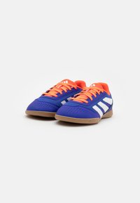Sport shoes with a blue mesh upper, orange accents, white stripes, and a tan rubber sole. Features perforations for breathability.