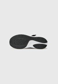Semelle de chaussure de sport avec un motif en caoutchouc noir et une semelle intermédiaire blanche. Design légèrement courbé pour une meilleure adhérence et stabilité.