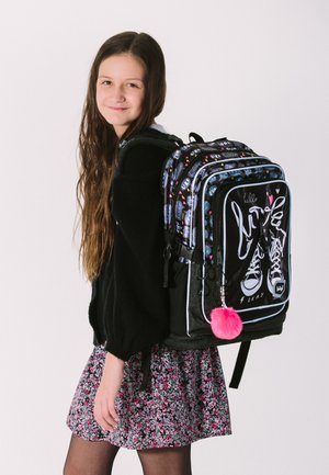 Schwarzer und blauer Rucksack mit mehreren Fächern, ausgestattet mit einem Sneaker-Motiv, einem pinken Pompon und bunten Mustern an den Riemen.