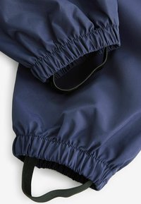 Marineblauwe windbreaker manchetten met elastische banden en zwarte webbing accenten. Het materiaal is glad en waterafstotend.