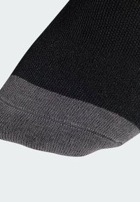 Calcetín negro con un puño acanalado gris, que presenta una textura suave y una vista en primer plano de la costura y el patrón del material.