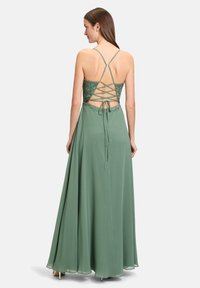 Grünes, bodenlanges Kleid mit Spitzenoberteil, Rücken mit Riemendesign und fließendem Stoff. Verfügt über einen gebundenen Akzent und ausgestellten Rock.