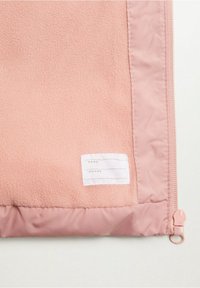 Růžové fleecové pouzdro s lesklým látkovým okrajem, vybavené štítkem pro jméno a telefonní číslo a bočním zipem pro zavření.