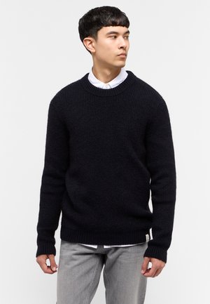 Marineblauer Strickpullover mit rundem Ausschnitt, gerippten Bündchen und Saum, mit einem strukturierten Muster und einem Logotag in der unteren linken Ecke.