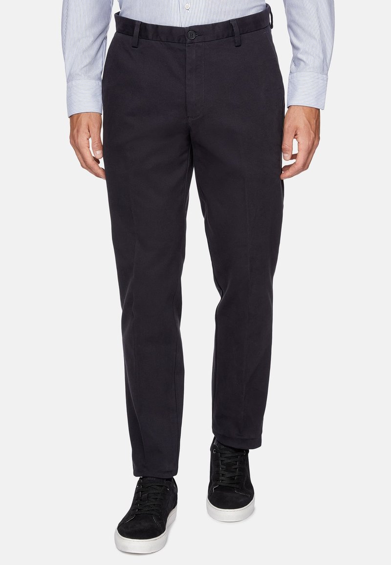 Dark navy cotton pants with a straight fit, front pockets, button closure, and back pockets. Paired with black sneakers.