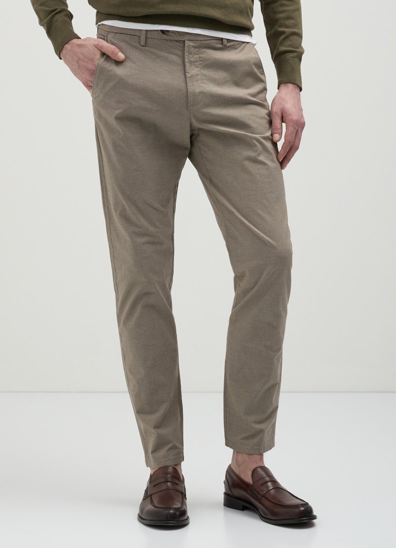 Chinos beige clair avec une coupe ajustée, en tissu mélangé coton, poches latérales et texture lisse, associés à des mocassins marron foncé.