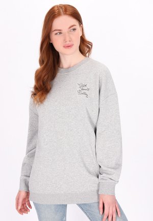 Grauer Pullover aus weichem Material, mit Rundhalsausschnitt, langen Ärmeln und einem kleinen schwarzen gestickten Design auf der Brust.