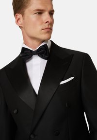 Čierne smokingové sako so saténovými klopami, dvojradové zapínanie, biela dress shirt a čierny motýlik. Obsahuje biely vreckový štvorec.