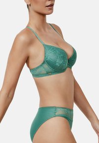 Groene kanten bh en bijpassende slipset met ingewikkelde bloemmotieven, doorschijnende kantdetails en verstelbare bandjes.