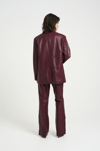 Maroon faux leather suit featuring a structured blazer with a crocodile texture and wide-leg pants, both displaying a smooth finish.