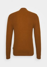 Geribbelde, lange mouwen trui in warm bruin. Strakke pasvorm met een kraag en een klein merklabel op de zijnaad. Zachte textuur.