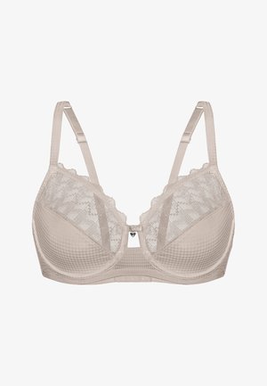 Soutien-gorge beige avec des détails en dentelle et un tissu texturé. Dispose de bretelles réglables, d'un soutien-gorge à armatures, et d'un petit accent en métal en forme de cœur.