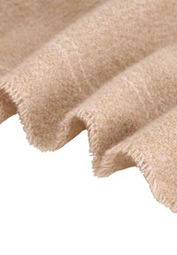 Ljust beige tyg med en texturerad väv, med naturliga fransar och mjuka, fallande veck.