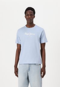 Ανοιχτό μπλε κοντομάνικο μπλουζάκι από βαμβάκι με στρογγυλή λαιμόκοψη και λευκό λογότυπο "Pepe Jeans London" στο στήθος. Φορεμένο με ανοιχτό μπλε τζιν.