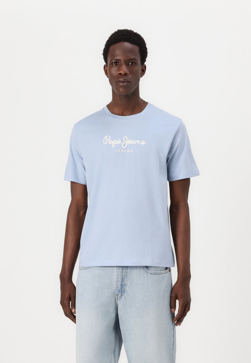 Ανοιχτό μπλε κοντομάνικο μπλουζάκι από βαμβάκι με στρογγυλή λαιμόκοψη και λευκό λογότυπο "Pepe Jeans London" στο στήθος. Φορεμένο με ανοιχτό μπλε τζιν.