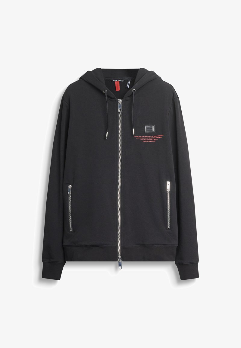 Felpa nera con zip e cappuccio, con cordini, due tasche frontali con zip, testo rosso e un piccolo patch rettangolare sul petto.