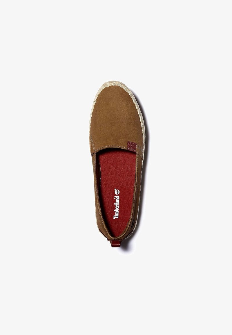Chaussure marron à enfiler avec une tige en daim, une semelle intérieure en textile rouge et une semelle extérieure en caoutchouc clair texturée. Logo Timberland visible.