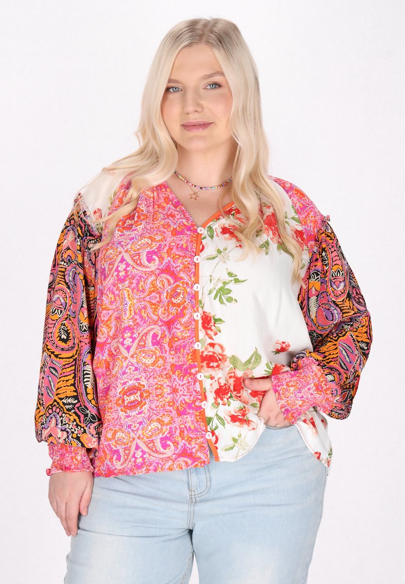 Blusa multicolore con motivi floreali e paisley, maniche lunghe a palloncino, chiusura a bottoni e tessuti misti nelle tonalità di rosa e bianco.