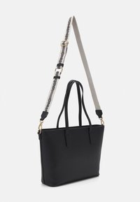 Black tote bag with smooth texture, featuring dual handles and a detachable grey strap marked with "Valentino" in black. Gold hardware accents.
