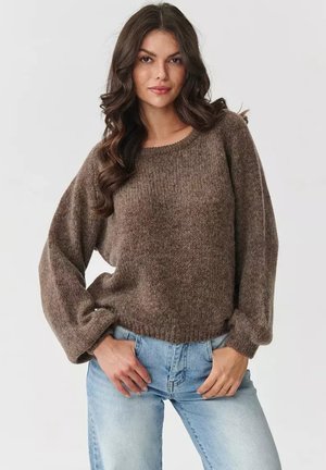 Brązowy sweter z wełny o teksturowym wykończeniu, okrągłym dekolcie i balonowych rękawach, w połączeniu z jasnoniebieskimi dżinsami.
