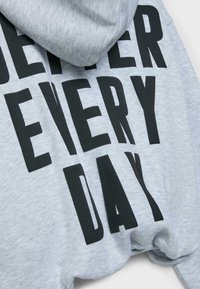 Grå hættetrøje med stort sort teksttryk, der lyder "BEDRE HVER DAG." Blødt stof, løs pasform og hættedesign.