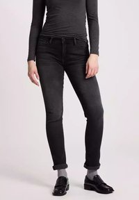 Czarne dżinsy o zwężającym się kroju, wykonane z denimu, charakteryzujące się miękką teksturą. Zawinięte mankiety, detale kieszeni oraz delikatne przetarcia na tkaninie.