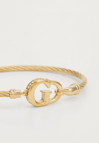 Gouden kabelarmband met een sluiting in opvallend 'G'-ontwerp en kleine ingelegde kristallen, met een gedraaide textuur.