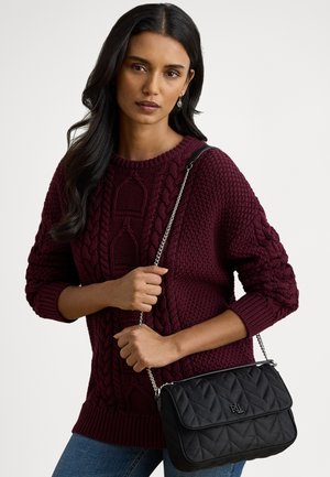 Bordowy sweter z grubym splotem i długimi rękawami, zestawiony z czarną pikowaną torebką na łańcuszku z wypukłym logo.