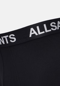 Schwarze Boxershorts mit einem breiten schwarzen Bund, auf dem "ALLSAINTS" in kontrastierendem Weiß aufgedruckt ist. Glatte Oberfläche, enganliegendes Design.