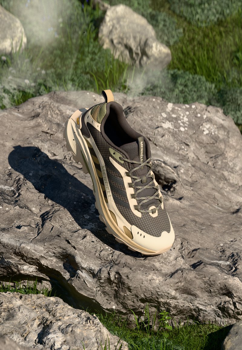 Athletic shoe features a brown and beige mesh upper, textured surface, and rubber sole with rugged tread. Accents include a khaki patch and logo.