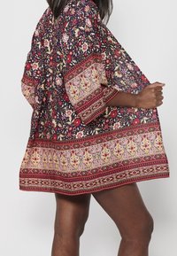 Kimonostijl tuniek met bloemenprint in navy en bordeaux, met een geprint zoom en brede mouwen, gemaakt van een lichtgewicht stof.