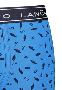 Niebieskie bokserki o żebrowanej strukturze, z granatowym paskiem w talii oraz wzorem ryb i fal w ciemnym niebieskim.