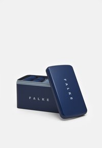 Caja metálica azul marino con tapa redondeada, con "FALKE" grabado en plata. Contiene calcetines enrollados de manera ordenada en diferentes tonos de azul y gris.