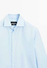 Lichtblauw gestreept overhemddetail met een klassieke kraag, een enkele pocket en witte knopen. Merklabel: Massimo Dutti.