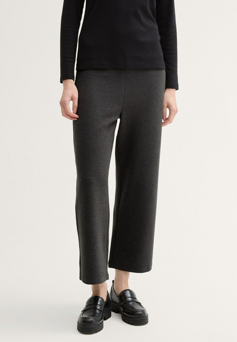 Pantalon large gris foncé en tissu doux, avec un design épuré, haut noir côtelé, et mocassins noirs épais avec semelle texturée.