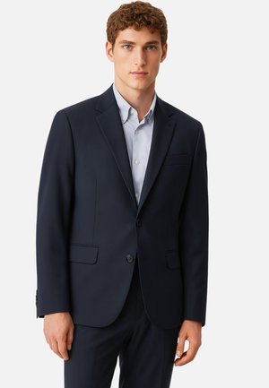 Giacca da abito blu navy su misura con revers a punta, due tasche frontali e chiusura a un bottone; tessuto liscio con minima consistenza.